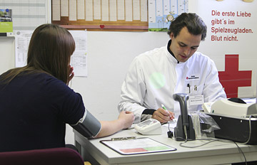 Foto: Blutdruckmessen und Ausfüllen eines Fragebogens durch den Arzt