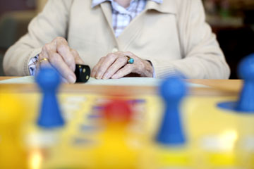 Seniorin vor Mensch-rgere-dich-nicht-Spiel